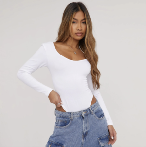 lady with brown hair wearing a long sleeve white bodysuit with blue jeans